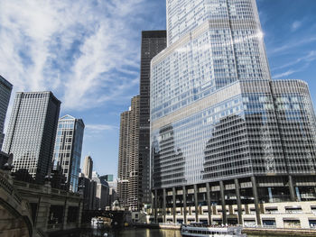 Low angle view of skyscrapers against cloudy sky