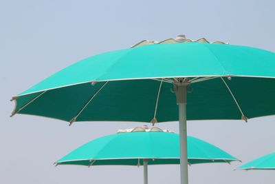 Low angle view of sunshades against clear sky