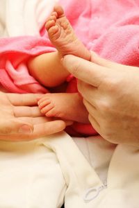 Cropped hands of mother touching baby feet on bed