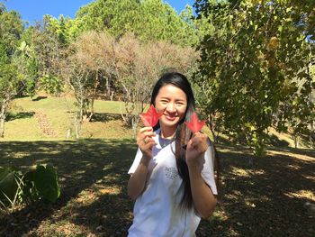 Portrait of young woman using mobile phone against trees