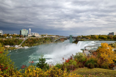 Scenic view of river by buildings against sky