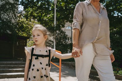 Senior woman holding hands while walking with granddaughter at kindergarten