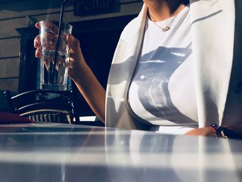 Midsection of woman holding drink at table in restaurant