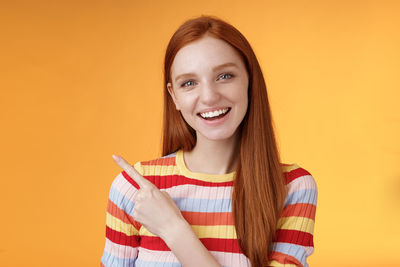 Portrait of smiling young woman against orange background