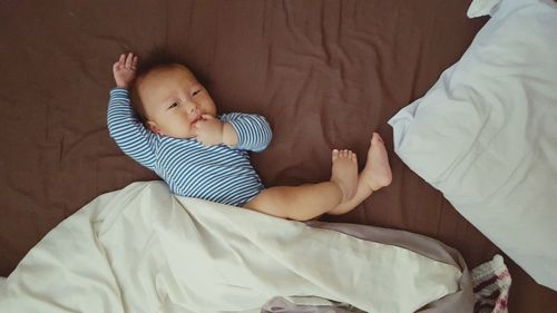 High angle portrait of baby boy lying on bed