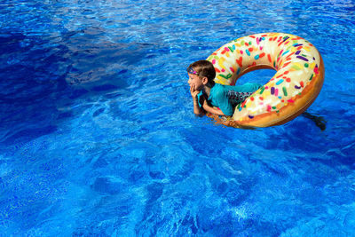 High angle view of boy floating in swimming pool