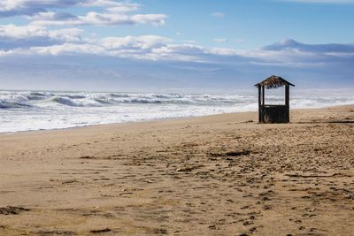Scenic view of beach against cloudy sky