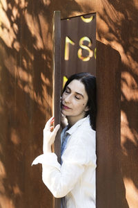 Portrait of young woman standing against wall