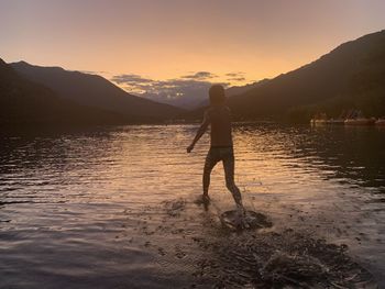 Man standing at beach against sky during sunset