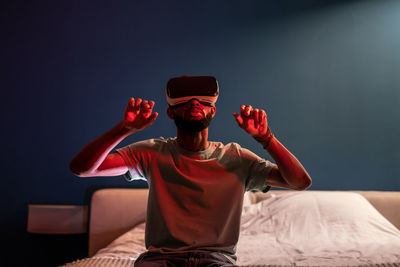 Portrait of young man sitting on bed at home