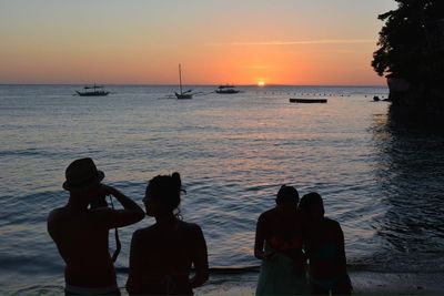 Silhouette of people on beach at sunset