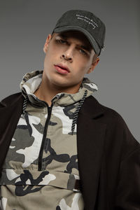 Portrait of young man standing against gray background