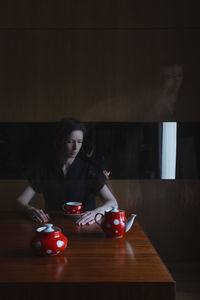 Mid adult woman with coffee on table at home