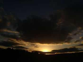 Silhouette landscape against dramatic sky at sunset