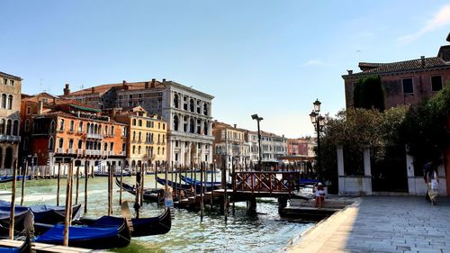 Boats moored at canal against buildings in city