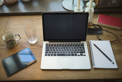 High angle view of technologies with note pad on table at home office