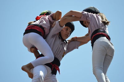 Low angle view of friends against clear sky