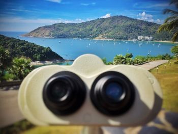 Close-up of coin-operated binoculars against mountains