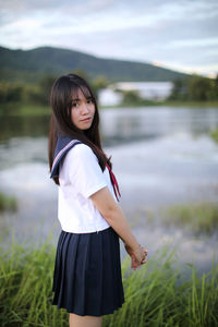 Portrait of young woman standing by lake