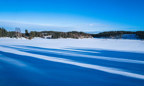 Scenic view of snow covered landscape against blue sky