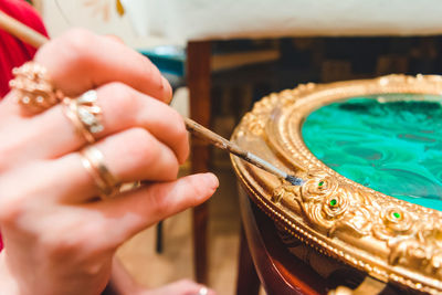 Cropped image of woman painting ornate container