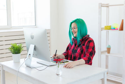 Portrait of woman using mobile phone while sitting on table