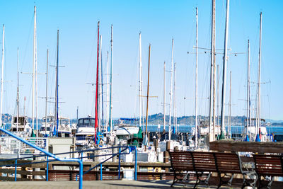 Sailboats moored at harbor against clear blue sky