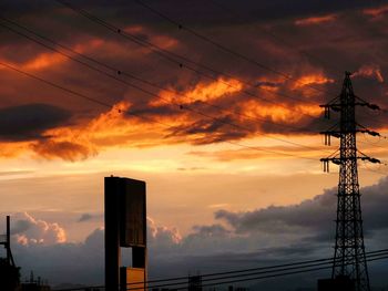 Low angle view of electricity pylon against cloudy sky