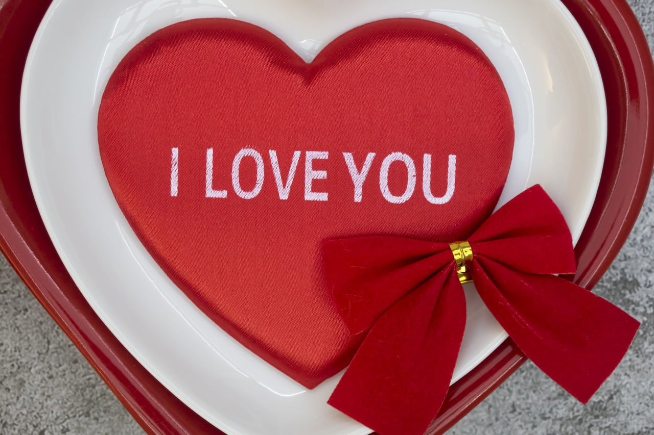 CLOSE-UP OF RED HEART SHAPE MADE FROM TEXT ON TABLE