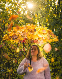 Female model holds an umbrella with autumn leaves on it in hand to the autumn beginning