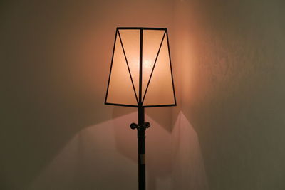 Illuminated lamp against wall at home