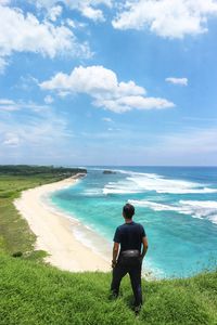 Rear view of woman standing on beach against sky