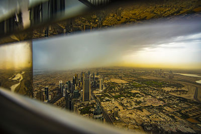 Aerial view of cityscape against sky seen through window during sunset