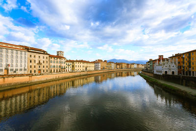 Arch bridge over canal amidst buildings in city against sky