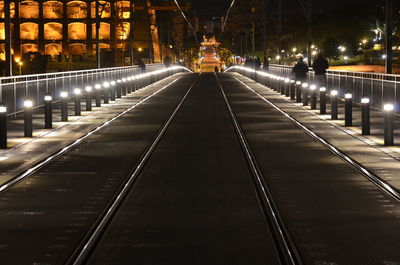 Illuminated railroad tracks in city at night