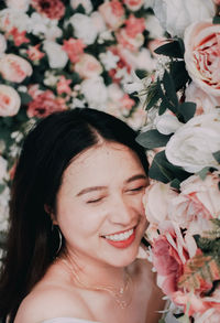 Close-up portrait of smiling woman with red flowers