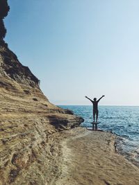 Man standing on beach against clear blue sky