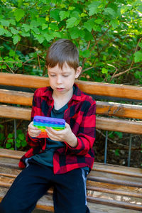 8-years old boy playing with popit in park. happy child with toy. kid wearing bright summer casual 