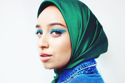 Close-up portrait of young woman wearing hijab against white background