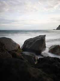 Scenic view of rocks on beach against sky