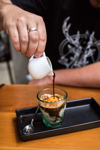 Midsection of man pouring coffee in cup on table