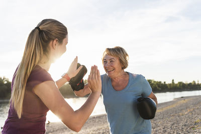 Grandmother doing boxing training with her graddaughter at the river