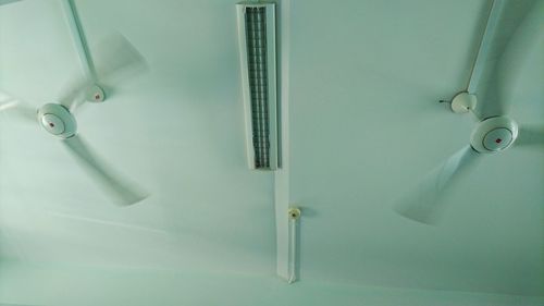 Low angle view of fans and light on ceiling