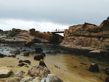 Rock formations on beach against sky