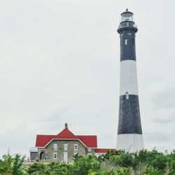 Low angle view of lighthouse by building against sky