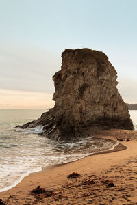 Rock formation on beach against sky