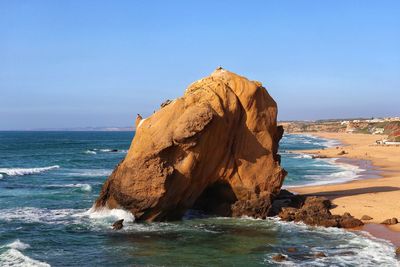 Rock formation on beach against clear sky