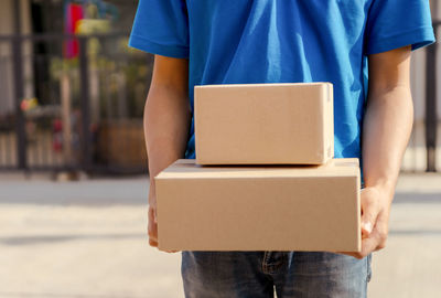 Midsection of man holding paper while standing in box