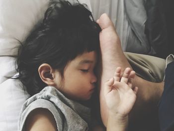 Low section of father with daughter sleeping on bed