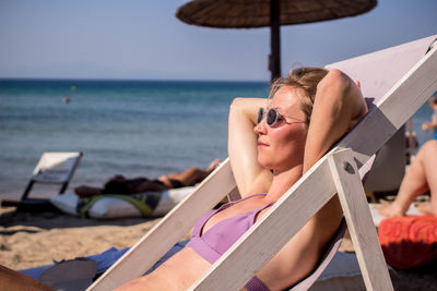 Woman relaxing in bikini on deck chair at beach